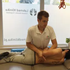 Fizjoterapeuta wykonuje masaż pleców, pomagając pacjentowi poczuć ulgę i dowiedzieć się, jak strzelić plecami.