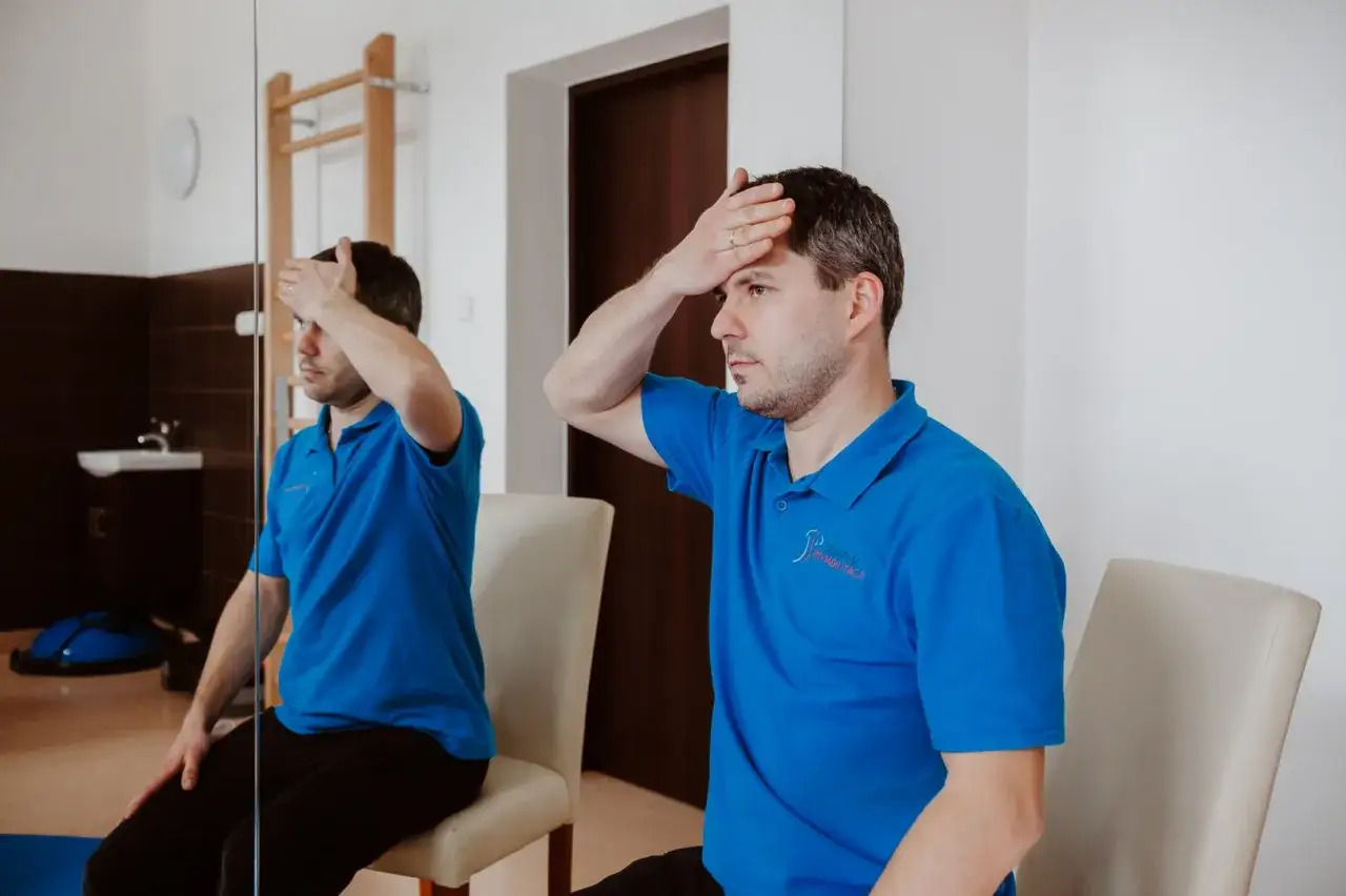 Fizjoterapeuta demonstruje ćwiczenie na ucisk nerwu szyjnego.